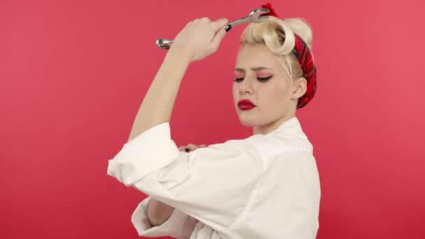 Подцепить блондинку с гаечным ключом и трогать бицепсы на розовом фоне — стоковое видео