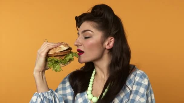 Pin up wanita tersenyum dan menggigit burger dengan mata tertutup — Stok Video