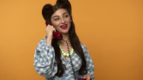 Smiling pin up woman looking around and talking on retro telephone — Stock Video