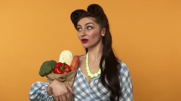 Pensive pin up customer woman holding bag with vegetables and looking around — Stock Video