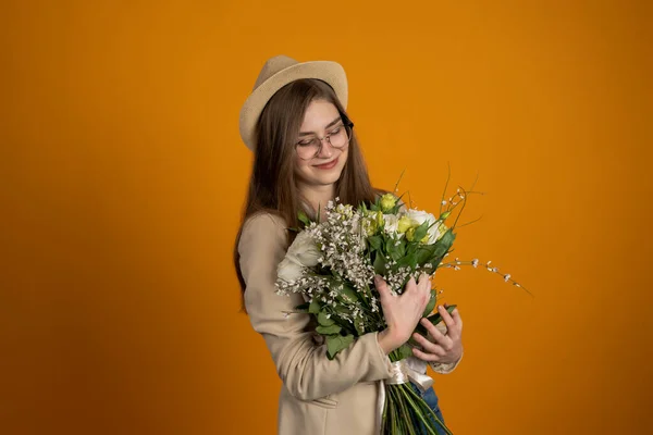 Очаровательная молодая женщина в шляпе и очках с цветами на желтом фоне — стоковое фото