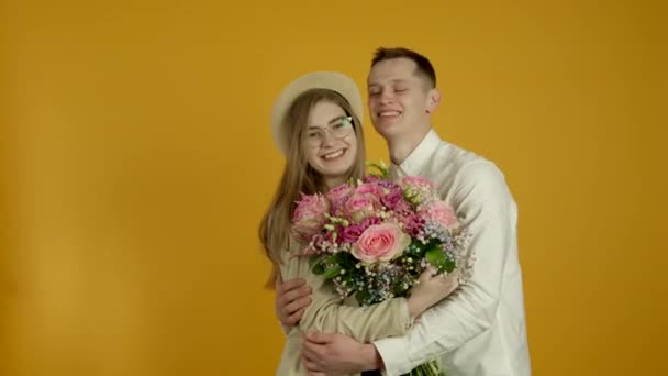 Pareja feliz con flores abrazando con sonrisa — Vídeos de Stock