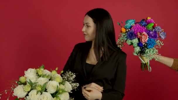 Pewna siebie brunetka stojąca z skrzyżowanymi ramionami i wybierająca kwiaty z uśmiechem — Wideo stockowe