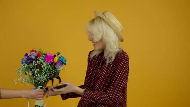 Красивая девушка со смартфоном принимает цветочный букет с счастливой улыбкой — стоковое видео