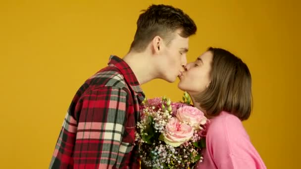 Vista lateral de pareja con flores besándose y mirándose con sonrisa — Vídeo de stock