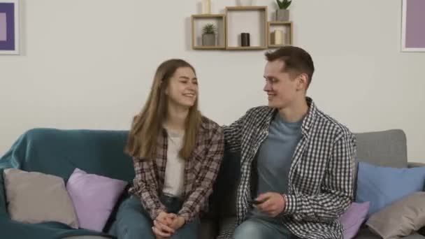 Entusiasmado casal abraçando no sofá enquanto assiste tv — Vídeo de Stock