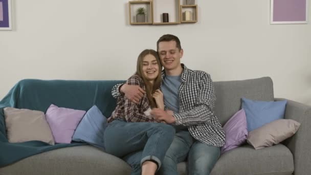 Ζευγάρι σε τζιν αγκαλιάζει και γελά βλέποντας τηλεόραση — Αρχείο Βίντεο