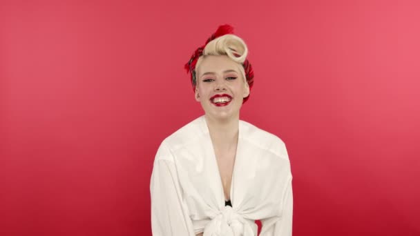 Gelukkig blond pin up meisje lachen op roze achtergrond — Stockvideo