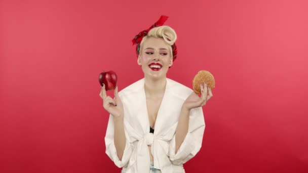 Leende stift upp kvinna håller äpple och hamburgare — Stockvideo