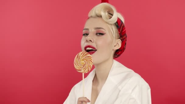 Blond pin up vrouw eten snoep en kijken naar de camera — Stockvideo