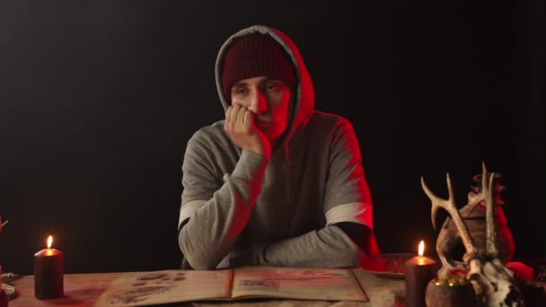 Pensive άνθρωπος στηρίγματα πρόσωπο με το χέρι στο τραπέζι με κεριά — Αρχείο Βίντεο