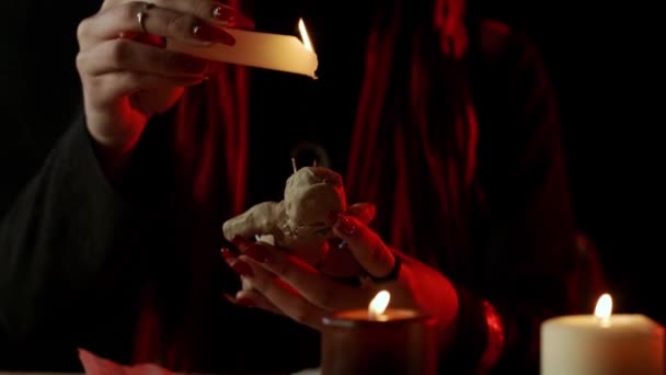 Обрезанный вид ведьмы со свечой, капающей воском на куклу вуду во время оккультного ритуала — стоковое видео