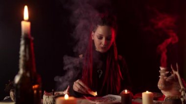 Odaklanmış cadı pentagrama duman içinde mum damlatıyor.