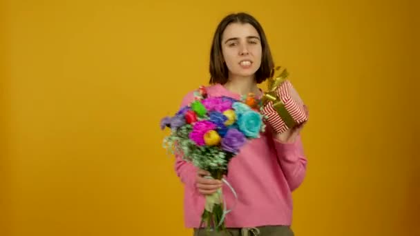 Ευτυχισμένο κορίτσι δείχνει λουλούδια και κουτί δώρου με χαμόγελο — Αρχείο Βίντεο