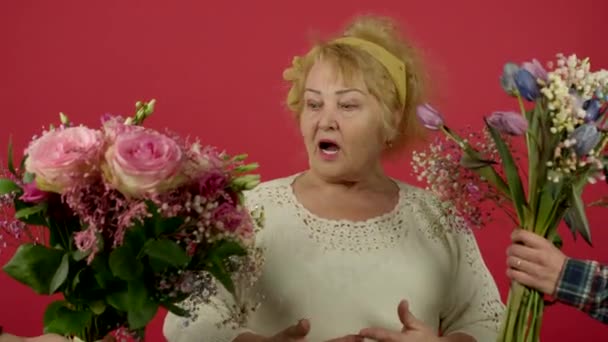 Vrolijke senior vrouw op zoek naar boeketten en het houden van eustoma bloemen met glimlach — Stockvideo