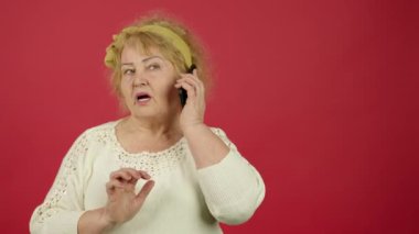 Endişeli yaşlı bir kadın akıllı telefondan yazı yazıyor ve arama yapmaya çalışıyor.