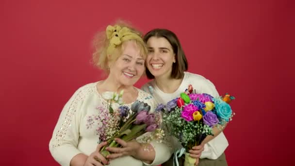 Grand-mère et petite-fille souriantes posant avec des fleurs — Video