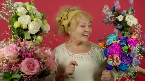 Возбужденная пожилая женщина танцует и смотрит на цветы — стоковое видео