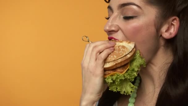 Alegre pin up mulher comer hambúrguer e piscar na câmera — Vídeo de Stock