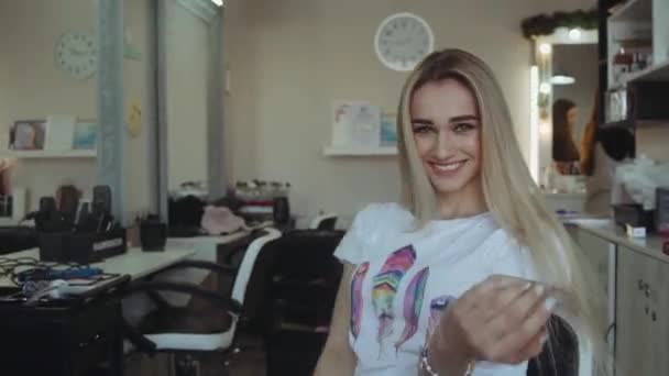 Retrato de la hermosa mujer sonriendo a la cámara en el salón de belleza. girando en silla — Vídeo de stock