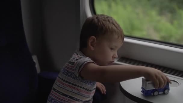 Petit garçon jouer avec des jouets tout en voyageant dans le train — Video