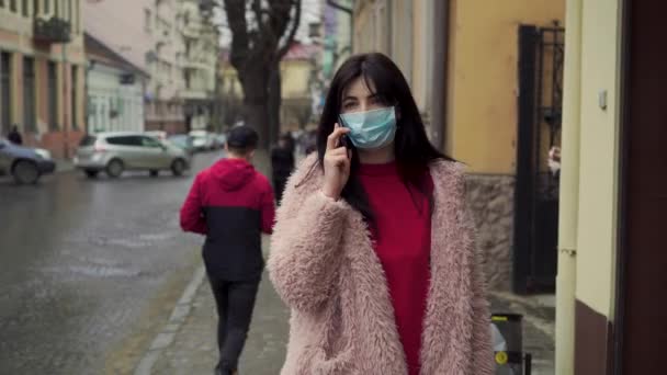 Woman walking on the street and speaking trough the phone. Pandemic of virus covid 19 — Stock Video