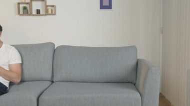 Genç bir adam evde tek başına oturuyor, telefona bakıyor, gülümsüyor, olumlu bir şekilde ayarlanıyor, karantinaya alınıyor.