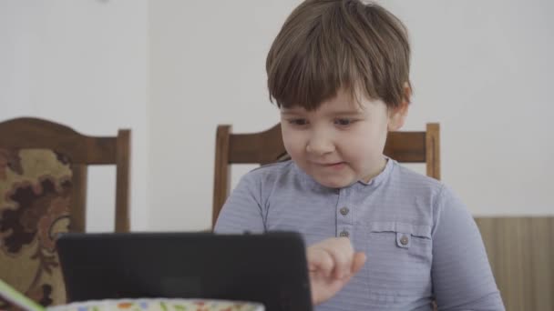Хлопчик дивиться мультфільм на планшеті під час роботи матері. Веселі емоції — стокове відео
