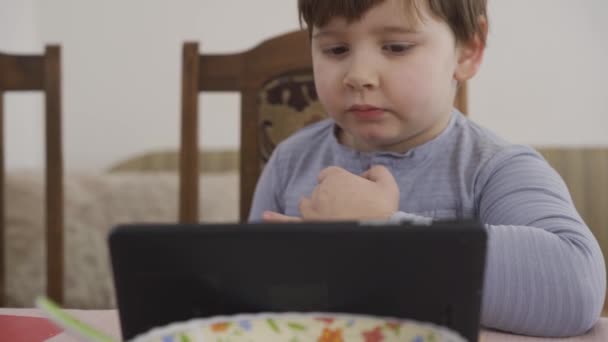 Rapaz aprende algo divertido no tablet. Aprendizagem pessoal. Babá online — Vídeo de Stock