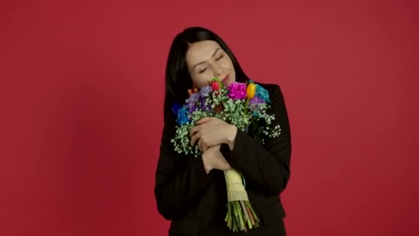 Pewna siebie brunetka kobieta trzyma kwiaty z uśmiechem — Wideo stockowe