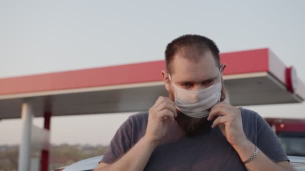 L'uomo indossa una maschera medica. Resta vicino a un'auto con dei bambini dentro. E 'calmo e felice, vigliacco 19 — Video Stock