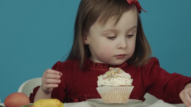 Dívka jí dort na velikonoce a barevné sladkosti z něj. Veselé Velikonoce — Stock video