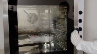 Kadın, profesyonel bir fırının kapısını açar. Metal, cam, raf, hamur işleri.