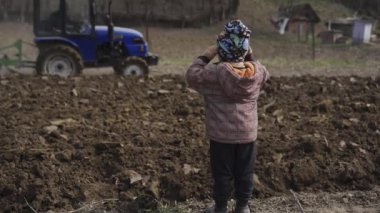 Küçük çocuk, traktörün toprağı ekmek için nasıl ektiğine bakar. Yiyecek için sebze ekiyorum.