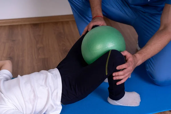 Ćwiczenia Pnf wykonywane przez pacjenta z pomocą fizjoterapeuty i zielonej kuli do masażu w domu opieki — Zdjęcie stockowe