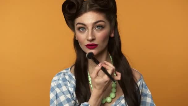 Cheerful pin up femme avec pinceau appliquer de la poudre sur le visage et clin d'oeil à la caméra — Video