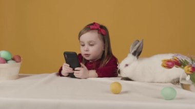 Kız çizgi filmi izliyor ve bir tavşanı okşuyor. Paskalya teması. Tatil