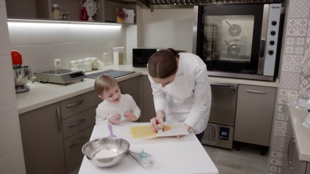 Madre e hijo cocinan en la cocina, túnica blanca, cocina brillante, niño sonríe — Vídeos de Stock