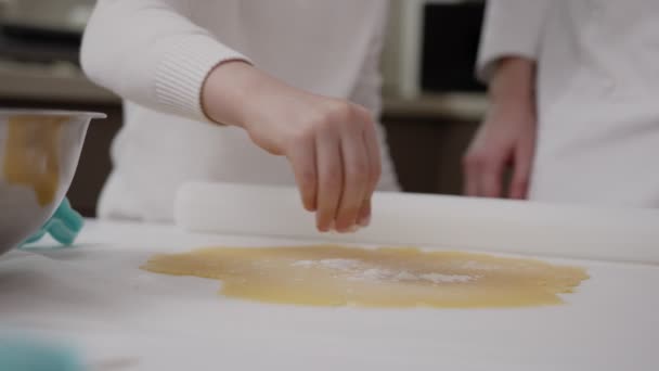 Vrouwen handen gesneden uit deeg koekjesvorm, kleine handen van het kind hulp, perfecte shortbread deeg op wit perkament — Stockvideo