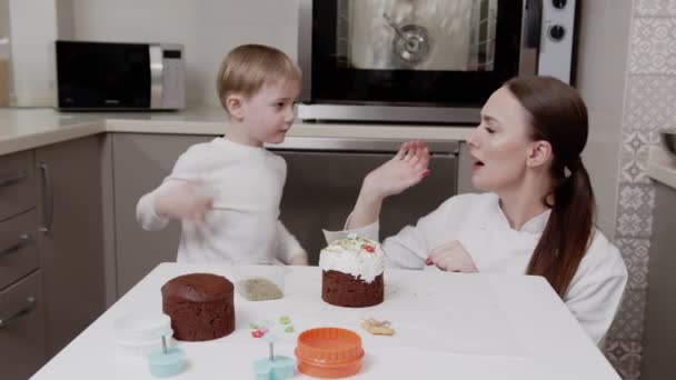 A mãe e o filho juntos fizeram um bolo de Páscoa, olham para ele, apreciam o seu trabalho. — Vídeo de Stock