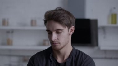 Kendine güvenen genç bir adamın yakın plan portresi, kafasını çevirir ve bakışlarını doğrudan kameraya çevirir, sürpriz bir hareket sergiler.