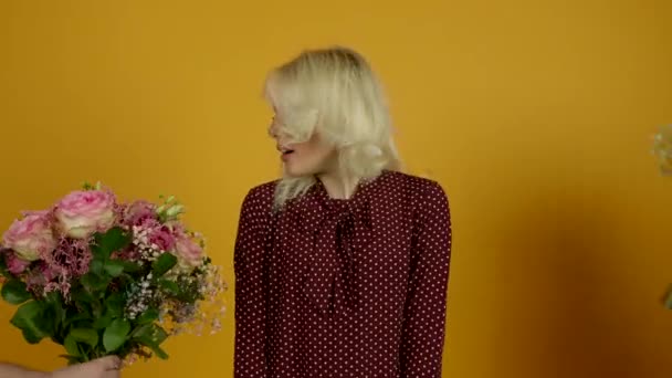 Surprised blonde girl looking at flowers and smiling at camera — Stock Video