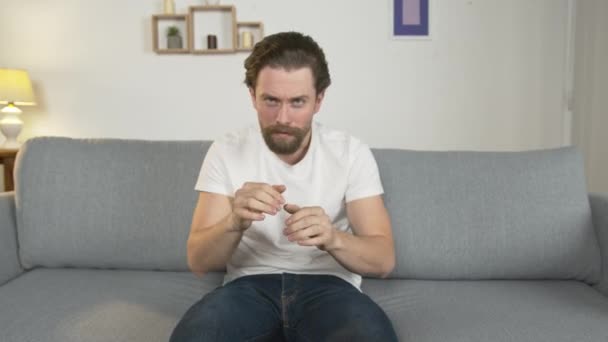 En man sitter på en soffa hemma, ensam, och tittar på en film, han är känslosam, reagerar på vad han såg — Stockvideo