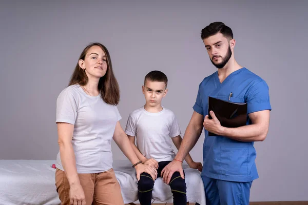 Lekarz prowadzący i matka małego pacjenta stoją blisko chłopca, trzymając go za ręce, koncepcję leczenia i wsparcia — Zdjęcie stockowe
