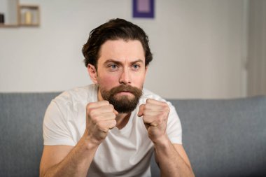 Bir adam evdeki bir kanepede tek başına oturur ve futbol maçını seyreder. Duygusaldır. Gördüklerine tepki verir..