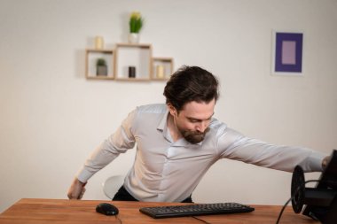 Ofis çalışanı, sakallı kızgın bir adam bilgisayarlı bir masada oturuyor, monitöre bakıyor, yorgun bir adam..