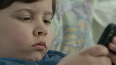 Bütün gün ebeveynlerinin ilgisizliğiyle telefonda çizgi film seyreden çocuk.