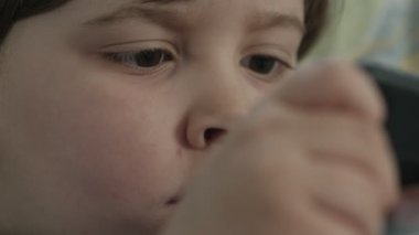 Bütün gün dikkatsiz bir çocuk telefonda çizgi film izlerken ebeveynler yakın mesafede çalışıyor.