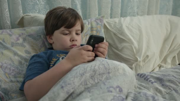 在父母忙的时候，小男孩在电话里看卡通片. — 图库视频影像