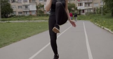 Gri spor üniformalı atletik kız koşu bandında antrenman yapıyor, koşuyor ve dizlerini kaldırıyor, sağlıklı yaşam tarzı kavramı.